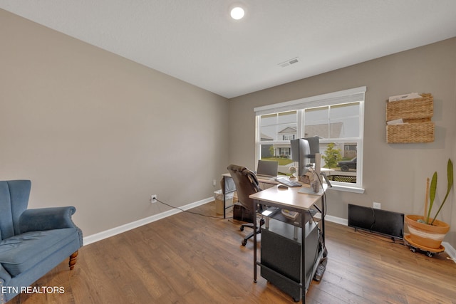 office space with baseboards, wood finished floors, and visible vents
