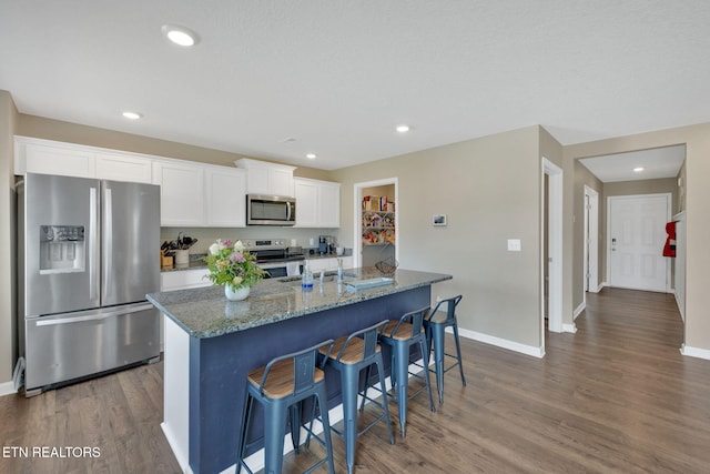 kitchen featuring dark wood-style flooring, baseboards, white cabinetry, stone counters, and stainless steel appliances