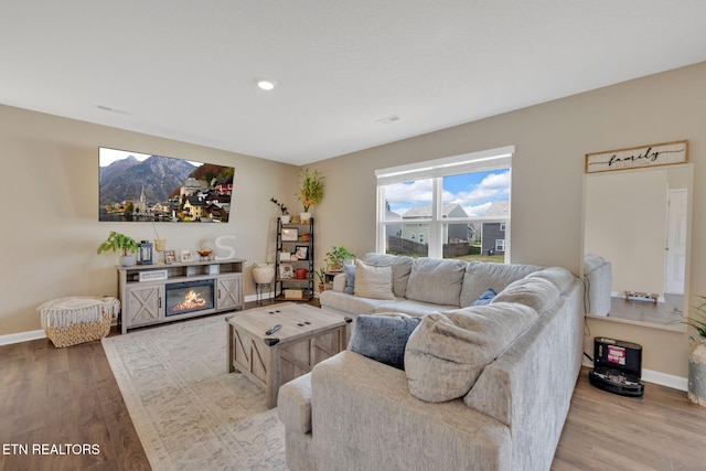 living room featuring baseboards, recessed lighting, and wood finished floors