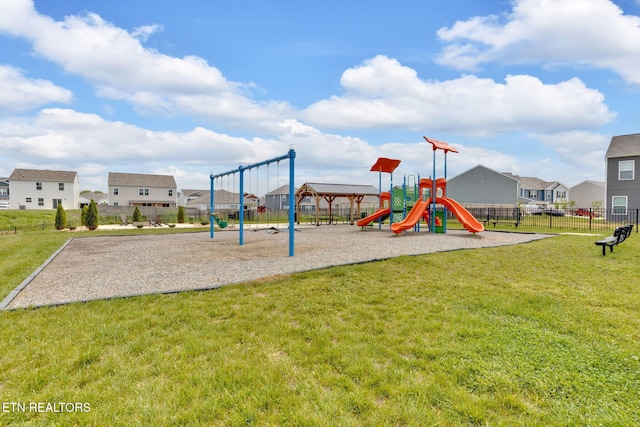 communal playground with a yard, fence, and a residential view