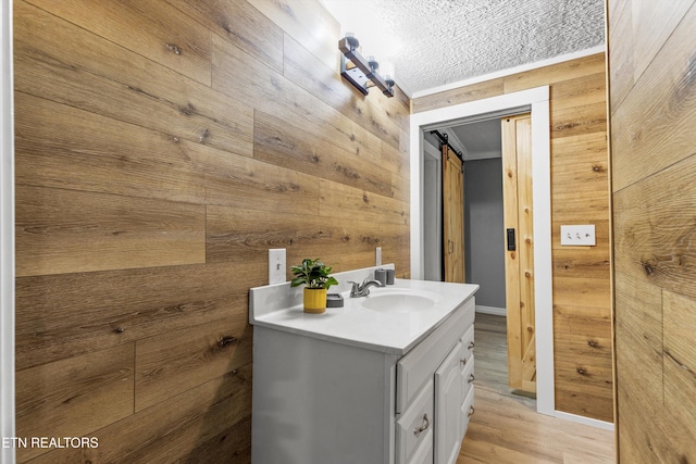 bathroom with wooden walls, a textured ceiling, wood finished floors, and vanity
