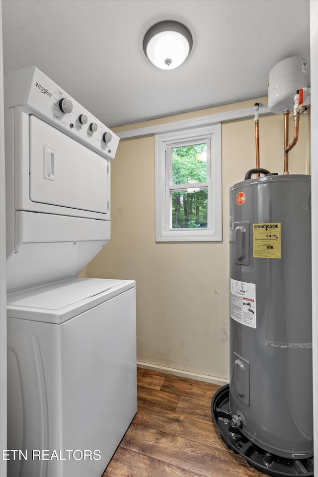 clothes washing area with laundry area, stacked washer / dryer, dark wood finished floors, baseboards, and water heater