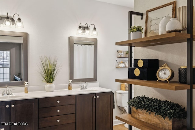 full bathroom with a sink, toilet, and double vanity