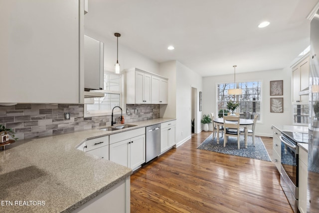 kitchen with tasteful backsplash, wood finished floors, a sink, stainless steel appliances, and white cabinetry