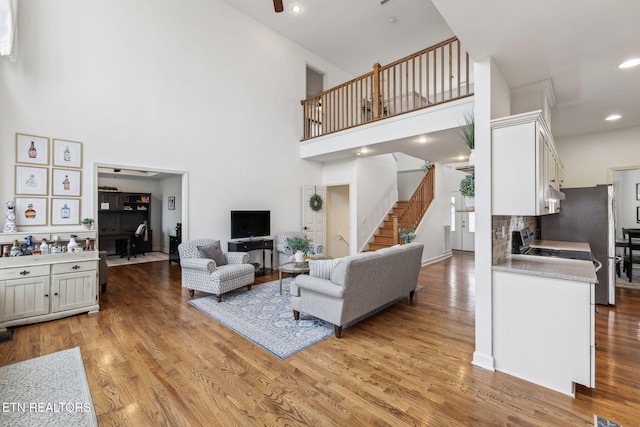 living room featuring light wood finished floors, stairway, and a towering ceiling
