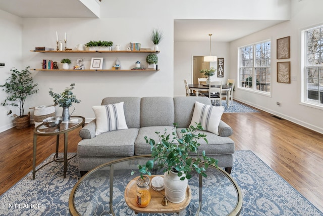 living area featuring baseboards, visible vents, and wood finished floors
