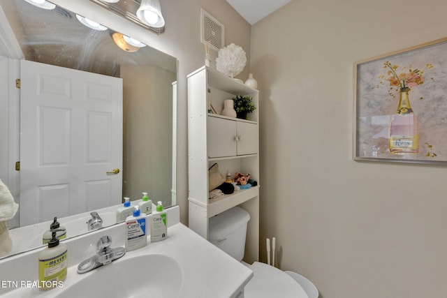 bathroom with vanity, toilet, and visible vents