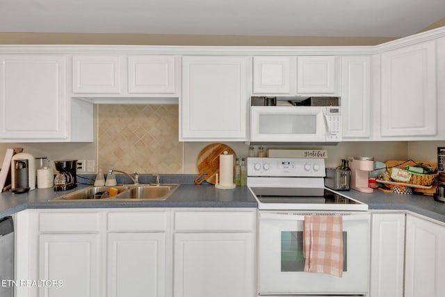 kitchen with dark countertops, a sink, white appliances, white cabinetry, and backsplash