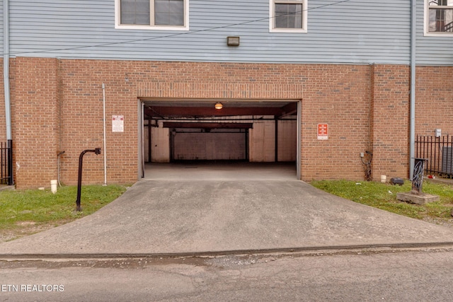 garage featuring fence and concrete driveway