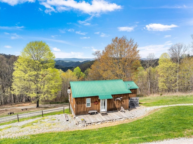 view of property's community featuring a lawn, fence, a deck, and a forest view