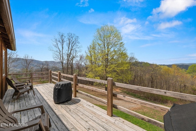 wooden deck with a view of trees and a mountain view
