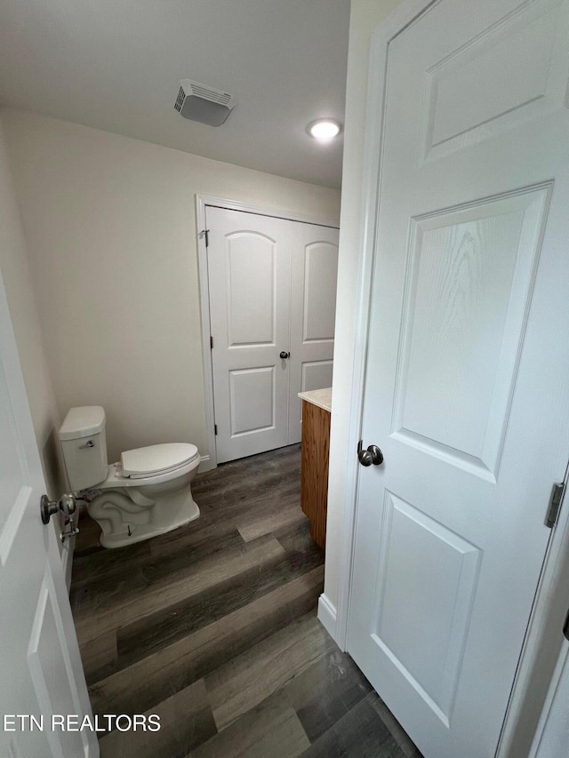 bathroom with toilet, visible vents, wood finished floors, and vanity