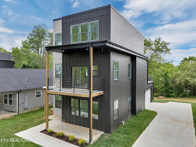 back of property featuring board and batten siding, an attached garage, and a balcony
