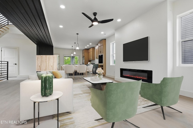 living room featuring a glass covered fireplace, a ceiling fan, recessed lighting, and light wood-style flooring