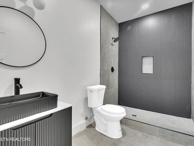 bathroom with tile patterned floors, a tile shower, and toilet