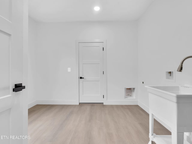 laundry area featuring baseboards, laundry area, light wood-style flooring, and hookup for a washing machine
