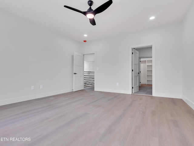 unfurnished bedroom featuring baseboards, ceiling fan, recessed lighting, light wood-type flooring, and a spacious closet