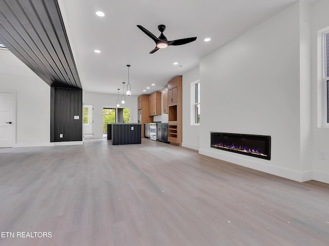 unfurnished living room featuring ceiling fan, a glass covered fireplace, light wood-style flooring, recessed lighting, and baseboards