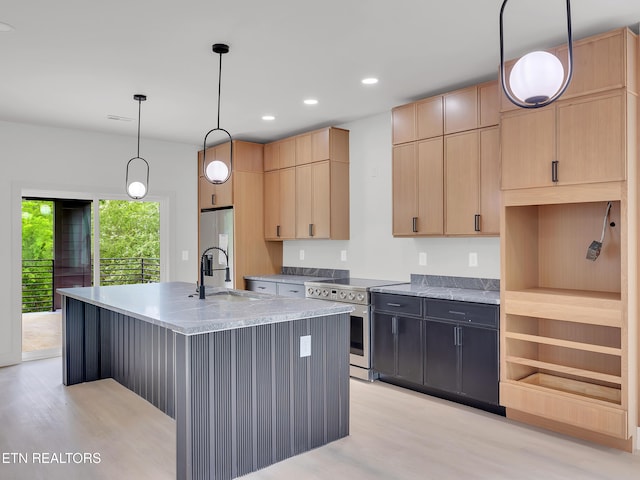 kitchen featuring appliances with stainless steel finishes, a sink, light brown cabinets, an island with sink, and light wood-type flooring