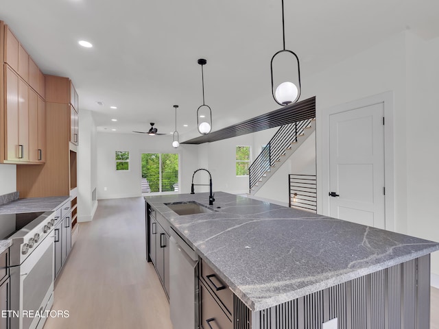 kitchen featuring stainless steel dishwasher, a ceiling fan, a spacious island, a sink, and light wood-style flooring