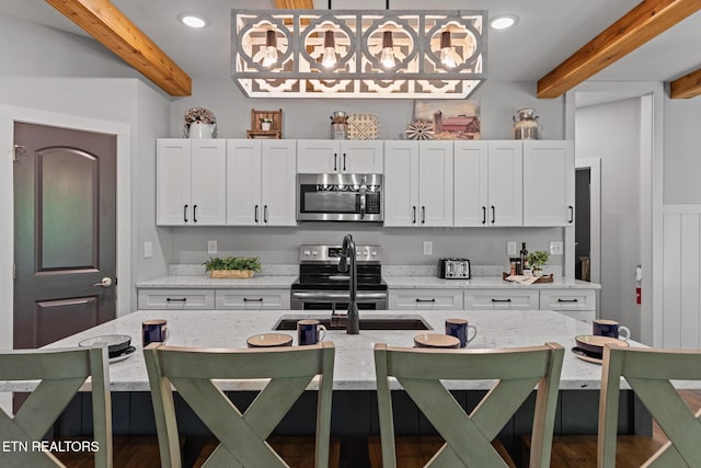 3487 Summit Trails Dr, Sevierville, TN 37862 - kitchen with pendant lighting, appliances with stainless steel finishes, white cabinets, beamed ceiling, and a breakfast bar