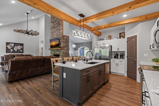 3487 Summit Trails Dr, Sevierville, TN 37862 - kitchen with open floor plan, a breakfast bar area, white cabinets, a sink, and stainless steel appliances
