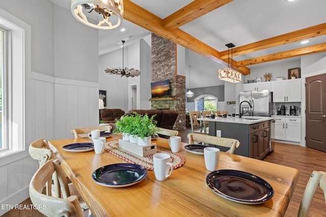 3487 Summit Trails Dr, Sevierville, TN 37862 - dining space featuring beamed ceiling, a decorative wall, wood finished floors, and a notable chandelier