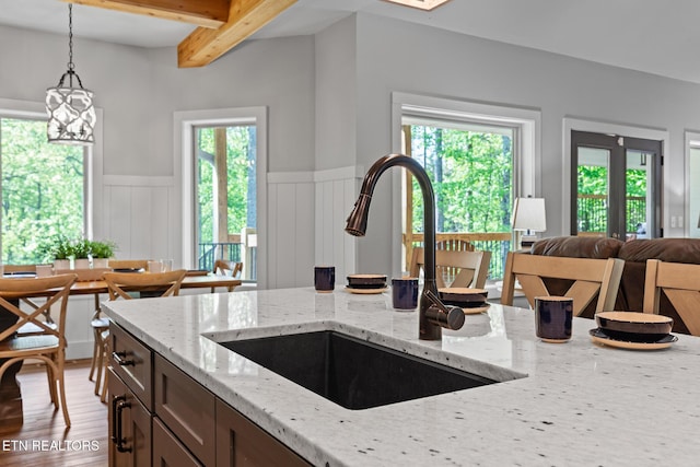 3487 Summit Trails Dr, Sevierville, TN 37862 - kitchen featuring pendant lighting, light stone countertops, a sink, a wainscoted wall, and beamed ceiling
