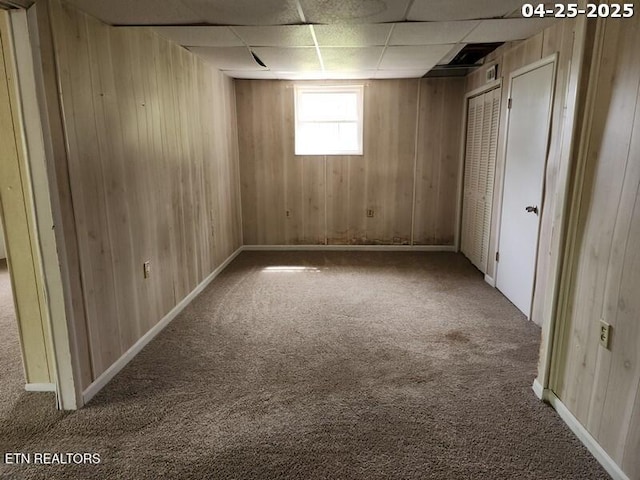 interior space with wooden walls, carpet, and a paneled ceiling