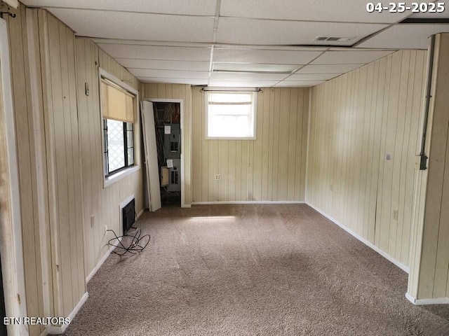 spare room with electric panel, visible vents, a paneled ceiling, carpet floors, and wooden walls