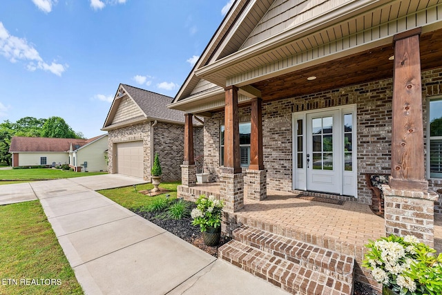 112 Naduli Trl, Vonore, TN 37885 - property entrance with a garage, driveway, brick siding, a porch, and a yard
