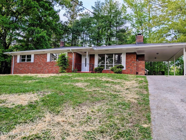 single story home featuring a chimney, a front yard, driveway, and brick siding