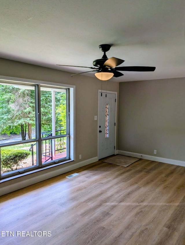 interior space featuring baseboards, a ceiling fan, wood finished floors, and visible vents