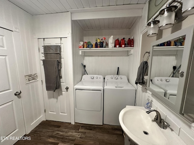 washroom featuring washing machine and clothes dryer, a sink, dark wood-type flooring, and wooden ceiling