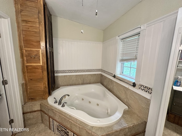 full bathroom with vaulted ceiling, a wainscoted wall, and a whirlpool tub