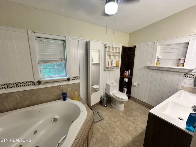 bathroom featuring toilet, a tub with jets, tile patterned floors, and a ceiling fan