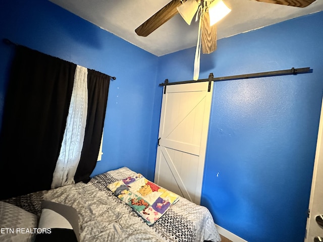 bedroom featuring a barn door and a ceiling fan