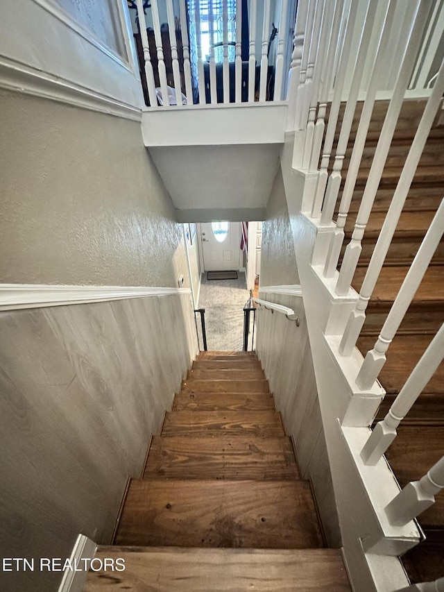 staircase with a towering ceiling and a textured wall