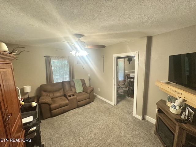 living area featuring ceiling fan, carpet, a textured ceiling, and baseboards
