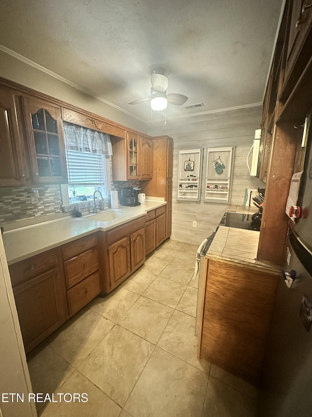kitchen with a sink, glass insert cabinets, light countertops, a ceiling fan, and range