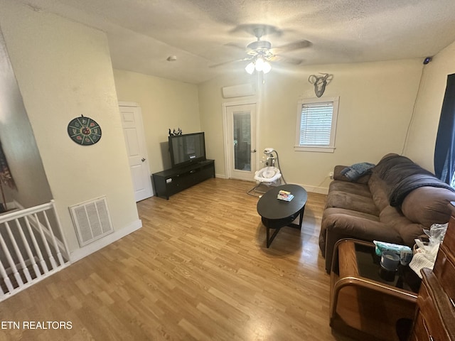 living area with light wood-style flooring, a ceiling fan, baseboards, and a textured ceiling