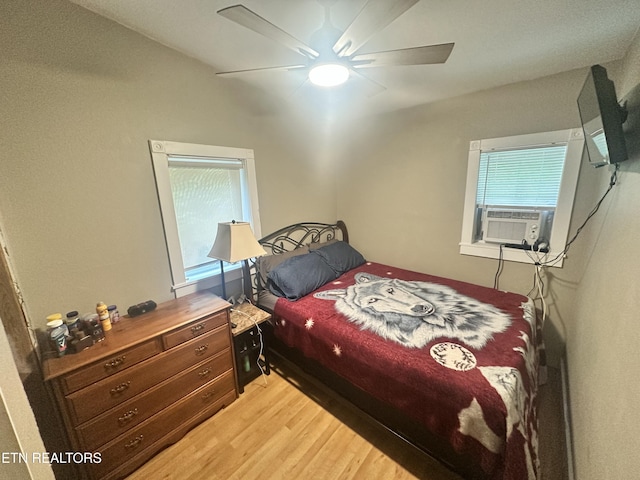 bedroom with cooling unit, light wood-type flooring, and ceiling fan