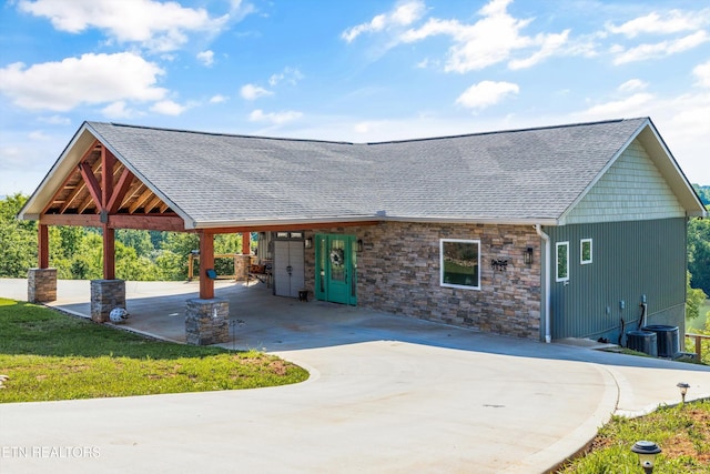 view of front of property featuring concrete driveway, roof with shingles, and stone siding