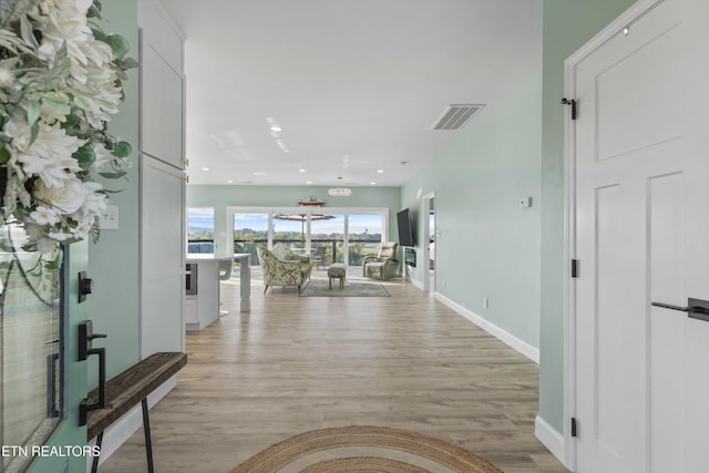 corridor featuring light wood finished floors, baseboards, and recessed lighting
