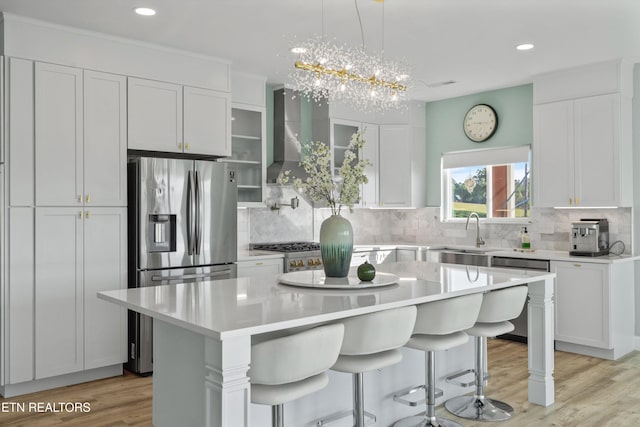kitchen with a sink, a center island, wall chimney exhaust hood, a kitchen bar, and light countertops