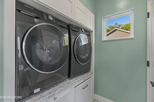washroom with washing machine and dryer, baseboards, and cabinet space