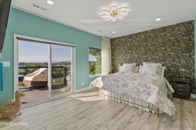 bedroom with access to outside, baseboards, wallpapered walls, wood finished floors, and an accent wall
