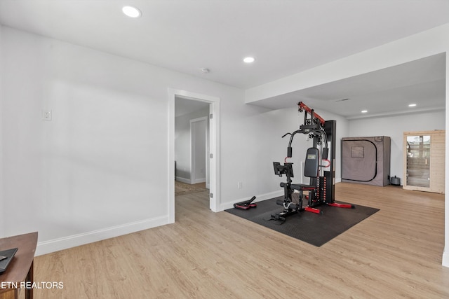 exercise area featuring wood finished floors, baseboards, and recessed lighting