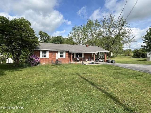 single story home with a chimney, a front yard, metal roof, and brick siding