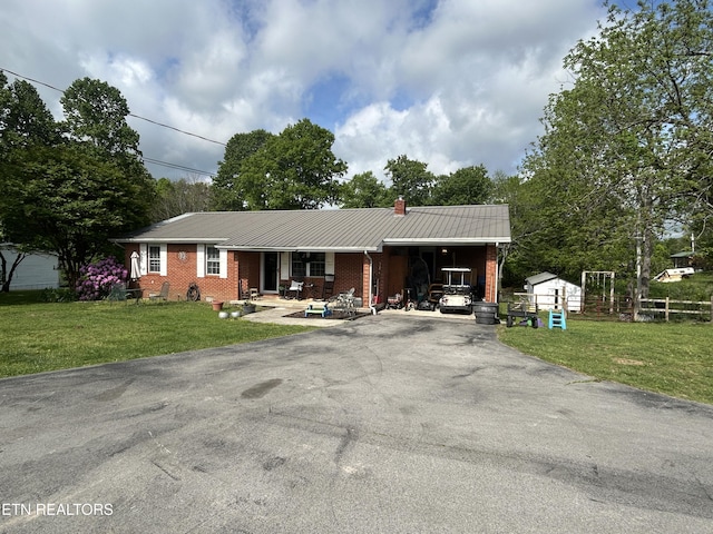 single story home featuring brick siding, aphalt driveway, a chimney, and a carport